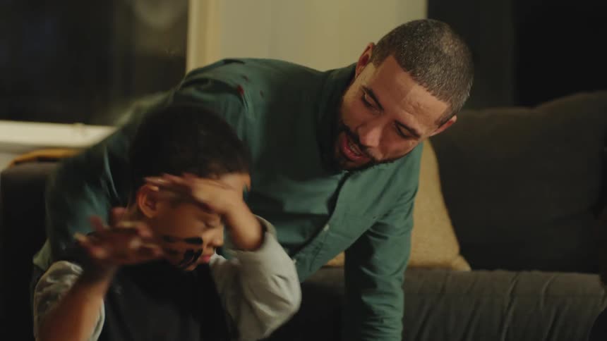Father talks to his children while they play with finger paint in the living room at home