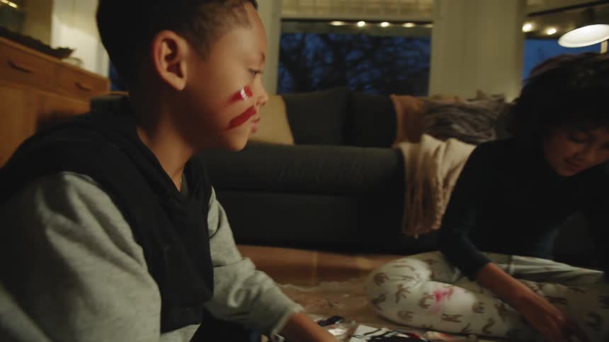 Two children are finger painting in the living room