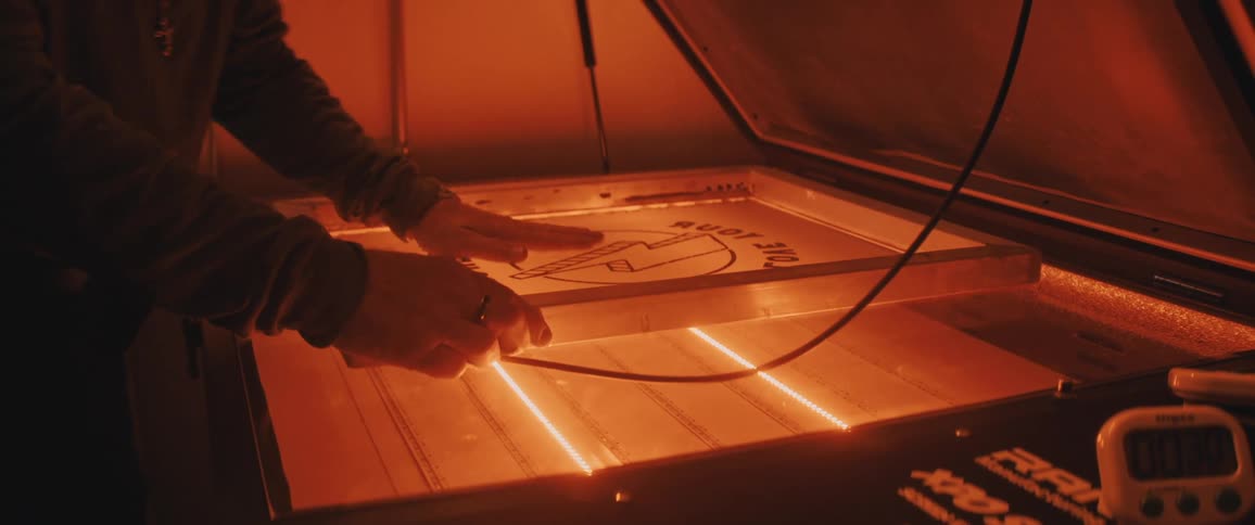A man is working in a darkroom getting ready to scan a graphic for screenprinting
