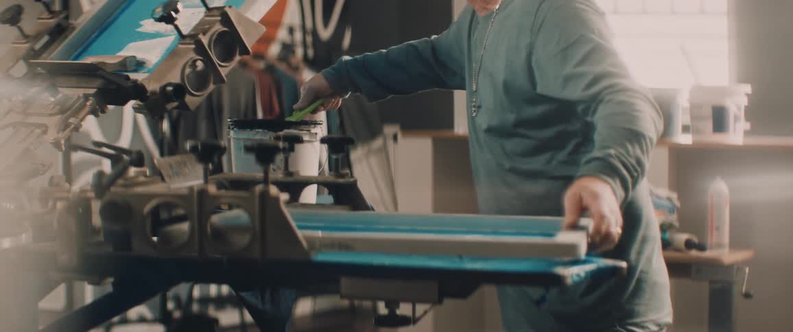A man smears paint on a panel attached to a large machine