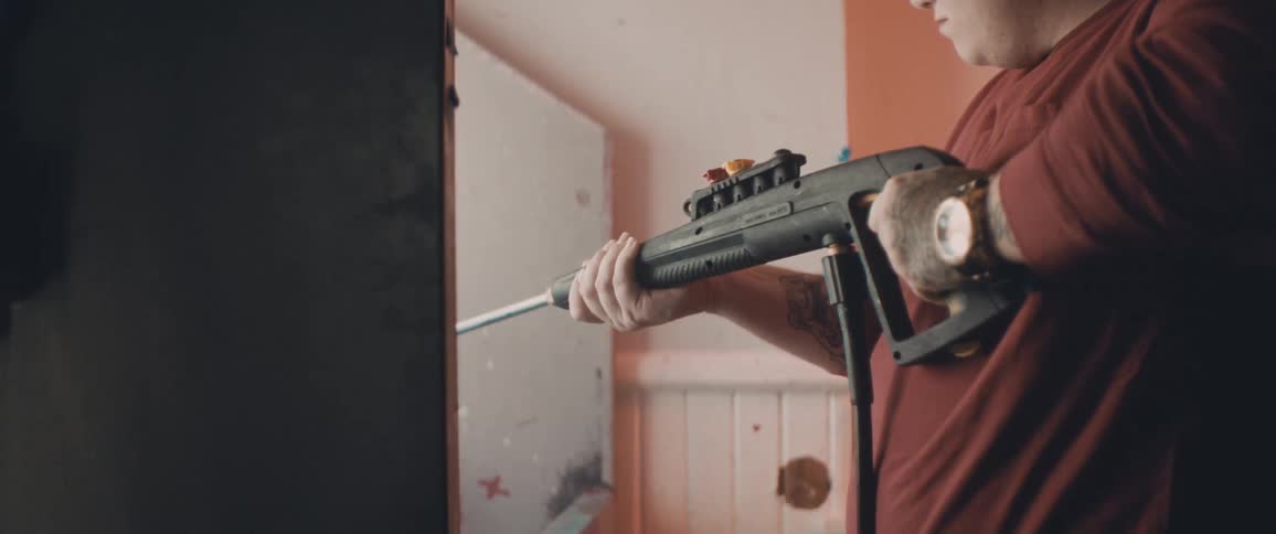 Man using a power washing machine to clean surfaces inside a room