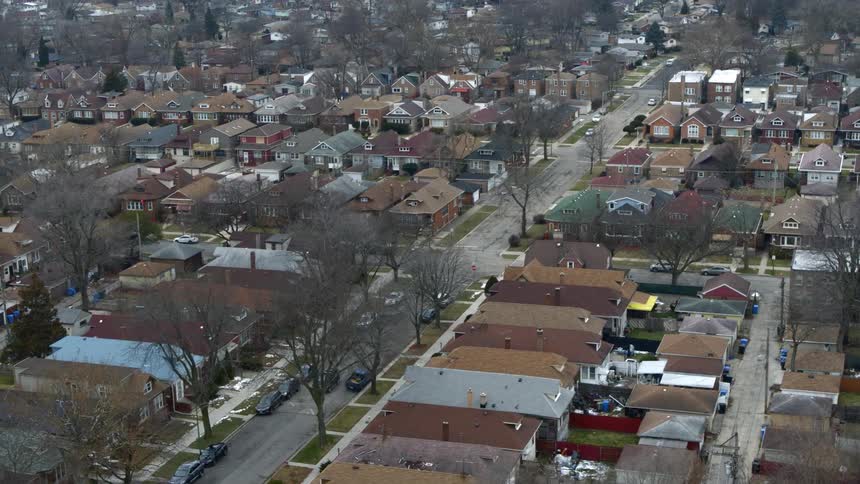 Car drives through residential neighborhood lined by leafless trees