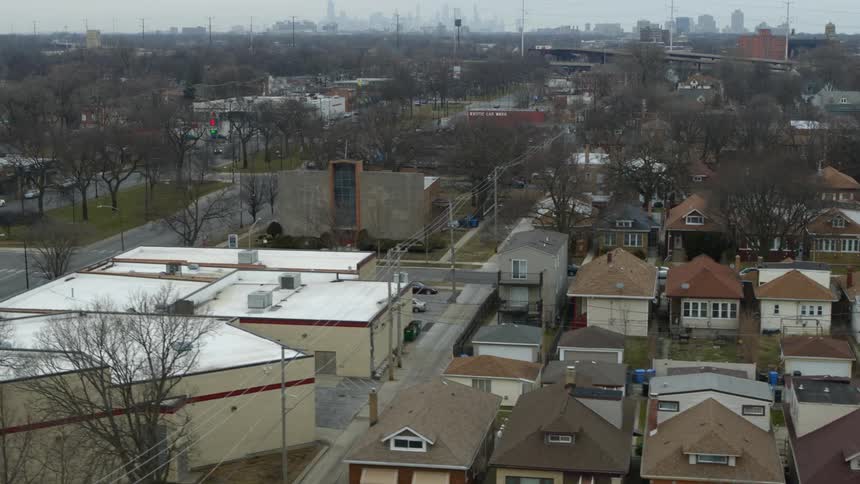 Aerial view of city houses with distant high rise buildings on cloudy day
