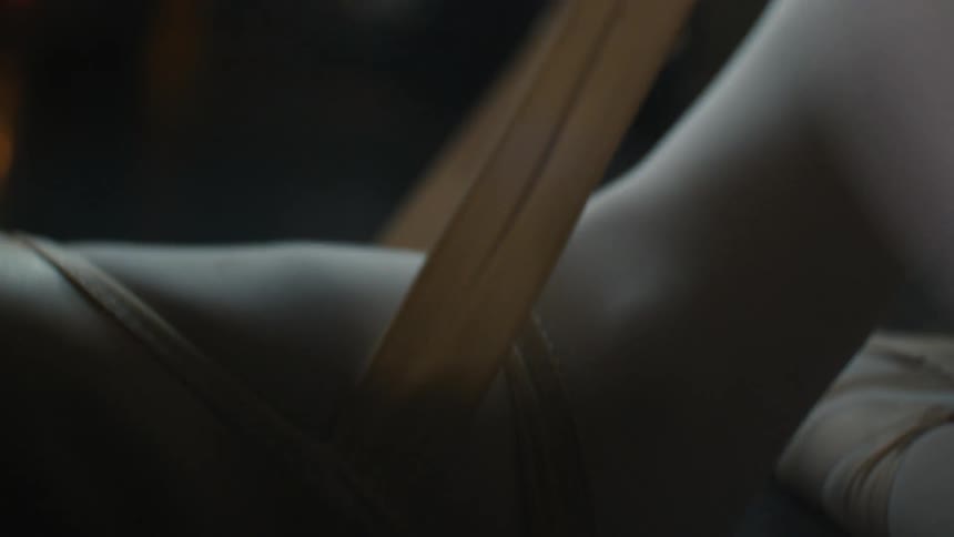 A ballet dancer tightens the ribbons on her pointe shoes