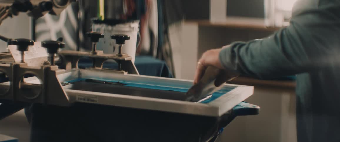A man is putting graphics on tshirts in the shop