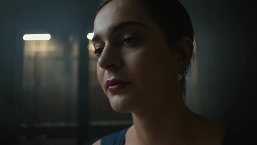 Close up of the face of a woman wearing makeup inside a dimly lit room
