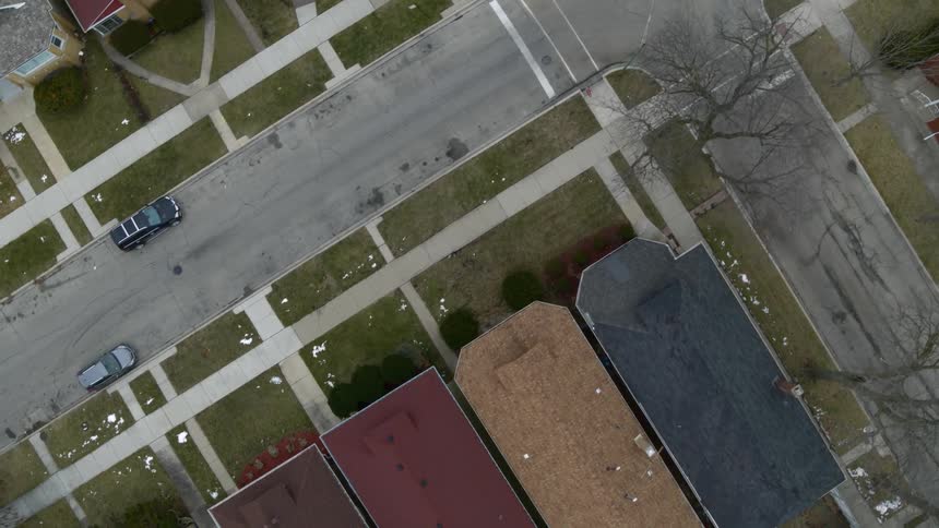 Aerial view of streets in a neighborhood lined with houses and cars parked on the side of the road