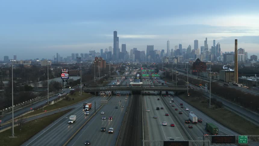 A busy freeway leads into a large city past an outdoor stadium