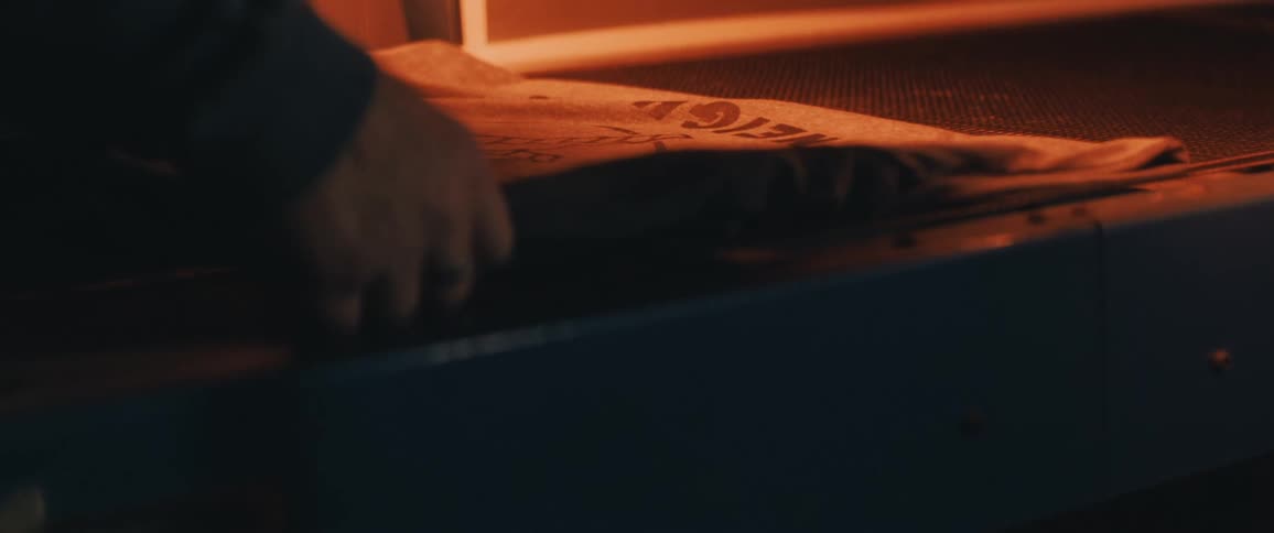 A man lies material on a conveyor belt and straightens it out