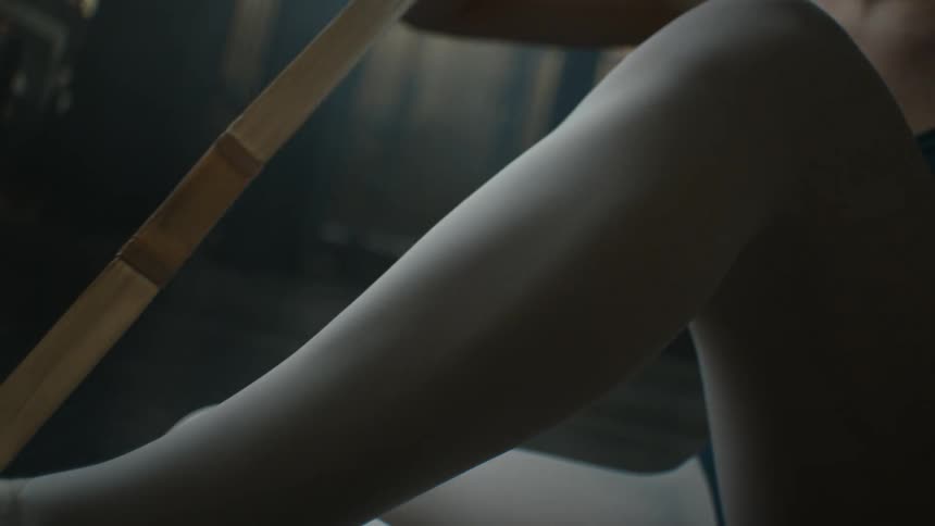 Ballerina sits on floor lacing up her toe shoes
