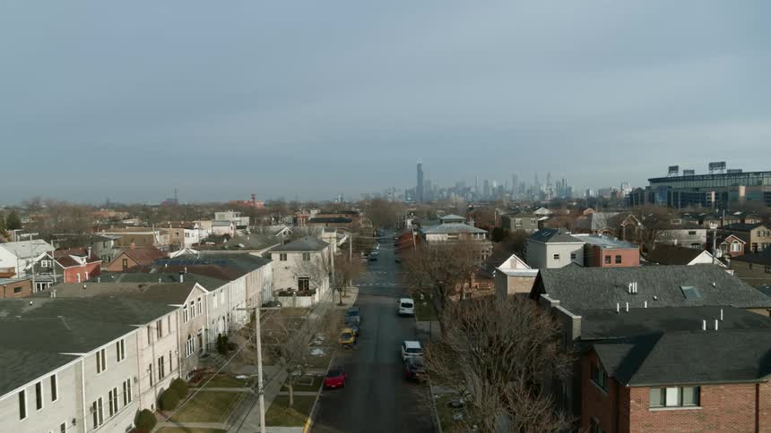 A city skyline is visible on the horizon at the end of a neighborhood street