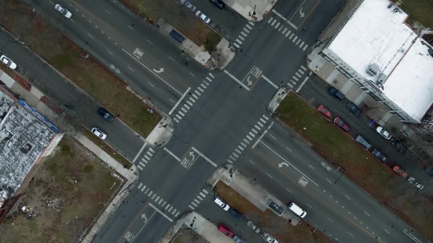 A top down aerial view of an intersection in an urban section of a city in the daytime