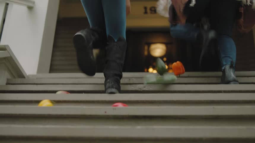 Woman climbing the stairs at home accidentally drop fruits and vegetables