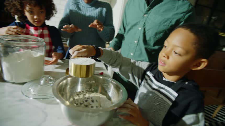 Family works together making mixture with flour and eggs