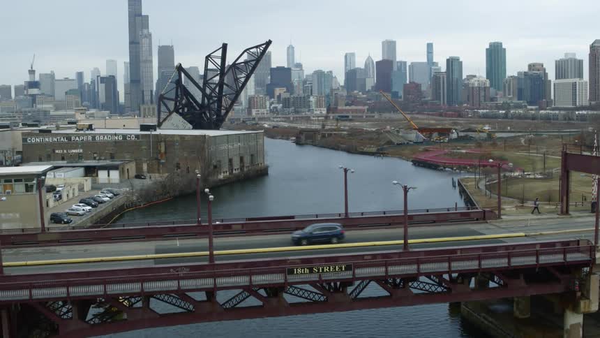 Traffic travels across a bridge spanning a river in a metropolis during the day