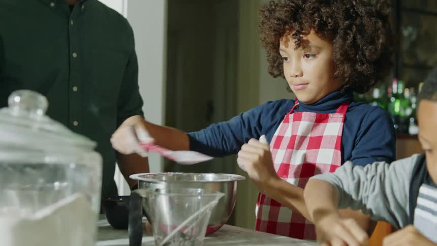 A family stands around the kitchen island making cookies together