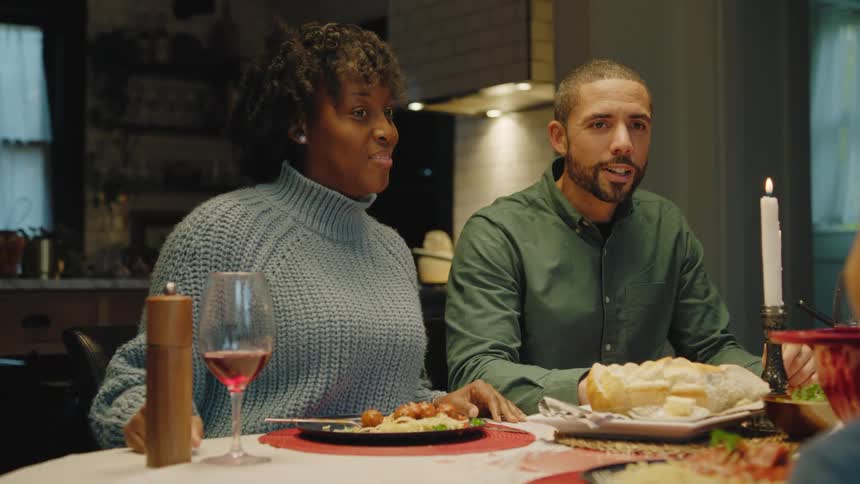 Mother and father smile while talking to their children at dinner table