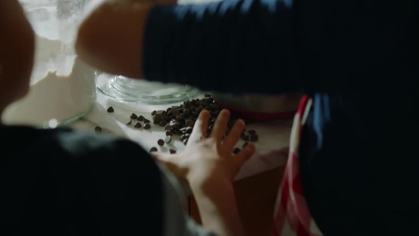 A family is in the kitchen and the children are putting berries in a mixing bowl