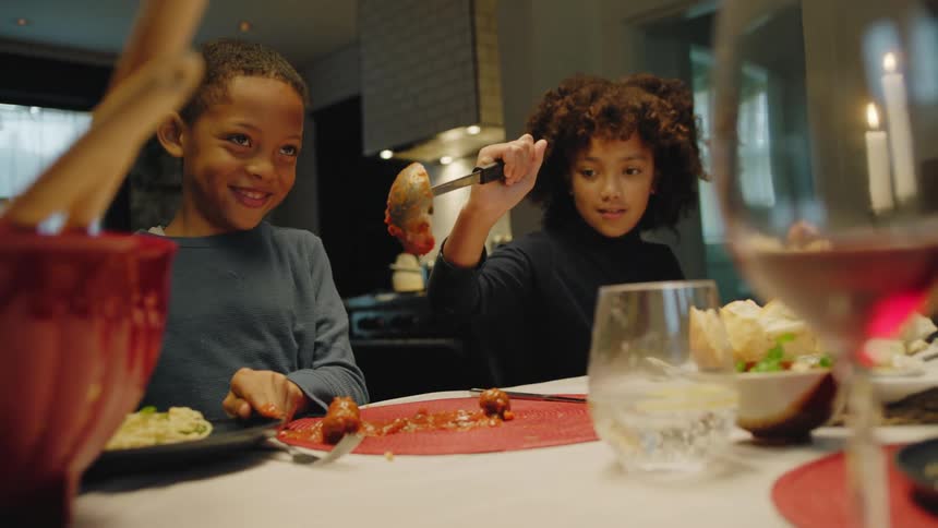 Brother tricks sister into pouring pasta sauce with meatballs over the dinning table