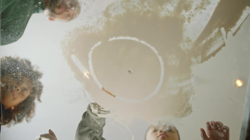 Family playing in the living room drawing with their fingers on flour