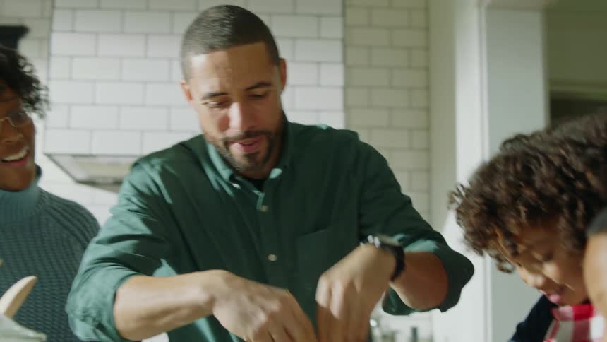 A family prepare food in the kitchen and make a mess