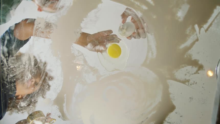 A child and parents baking with an egg on a table