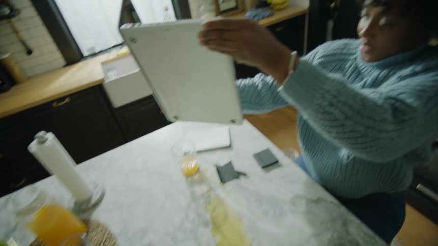 Woman spills juice onto laptop keyboard then hurries to clean it with mans help