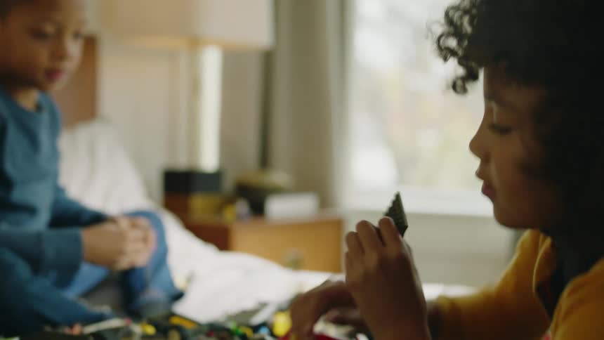 Two children play with toys in bed