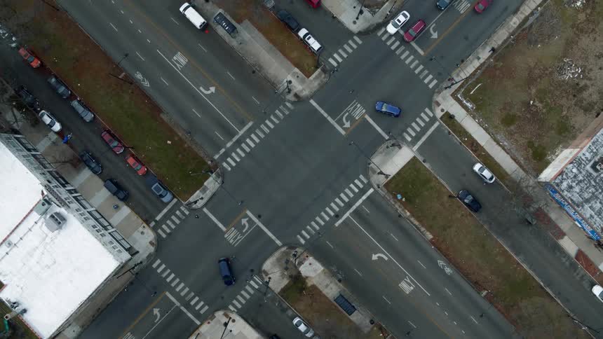 Top down aerial view vehicles driving over an intersection on the road