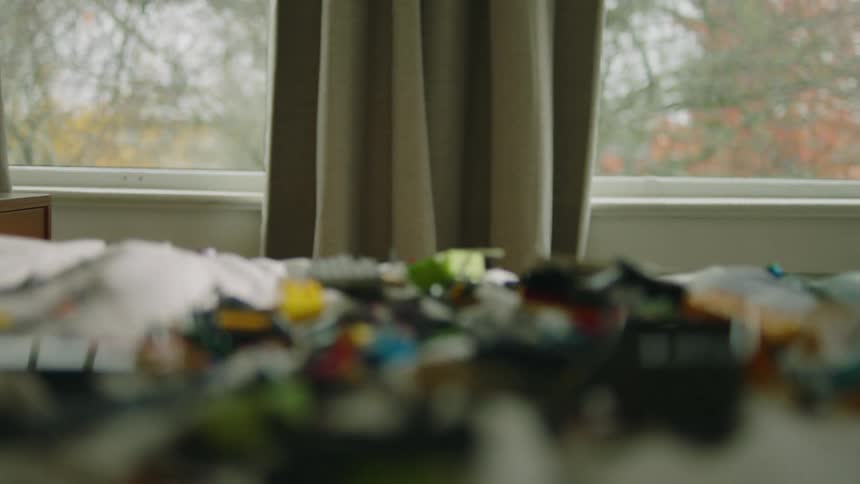 Children stand from behind the bed throwing toys on the bed