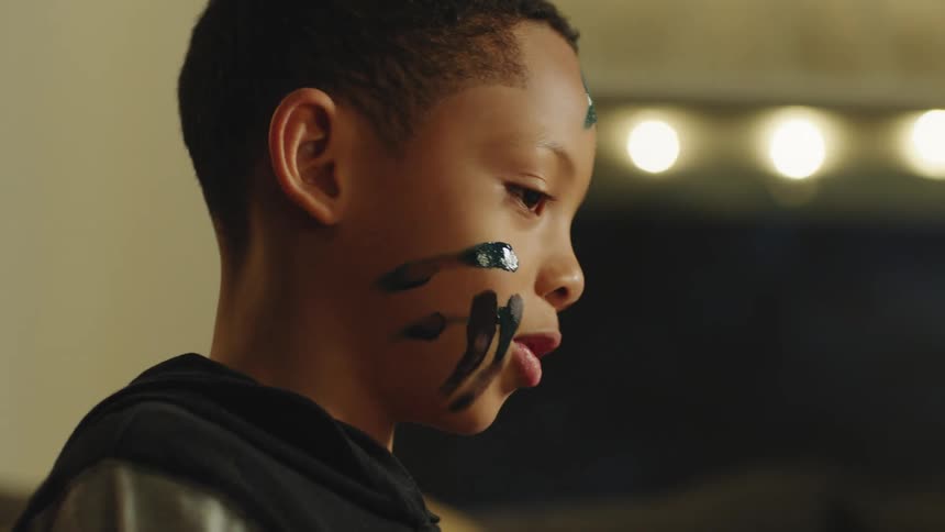 Boy with paint on his face dodges as someone with paint smeared fingers tries to put more paint on him