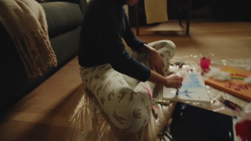 People play with paints sitting on plastic counted living room floor