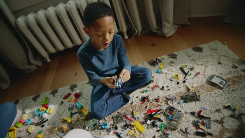 A young boy is sitting on a rug on the floor playing with toys