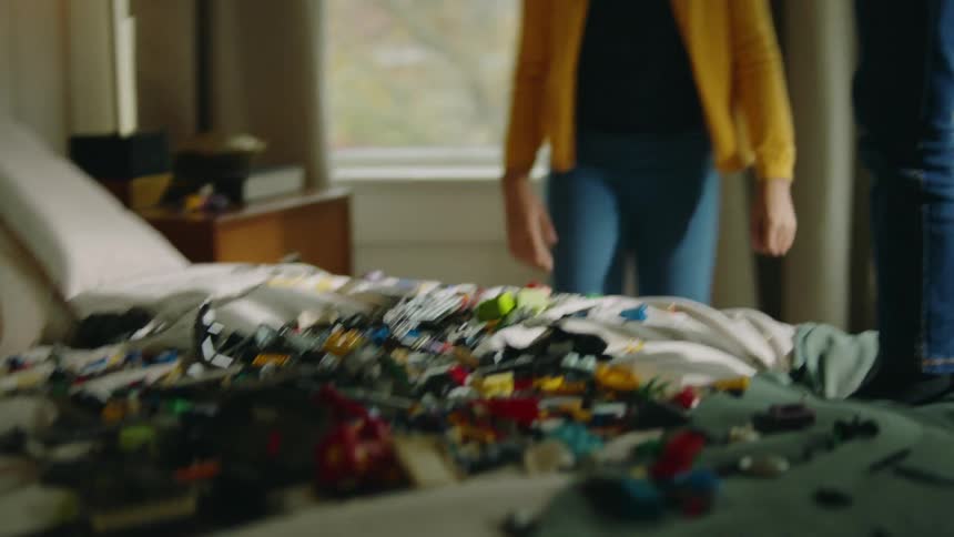 Brother climbs onto bed to drop toy pieces onto it then he and sister dance
