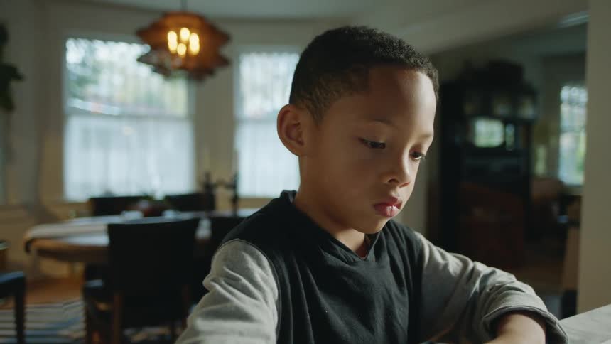 A young boy is drawing a picture with a green marker
