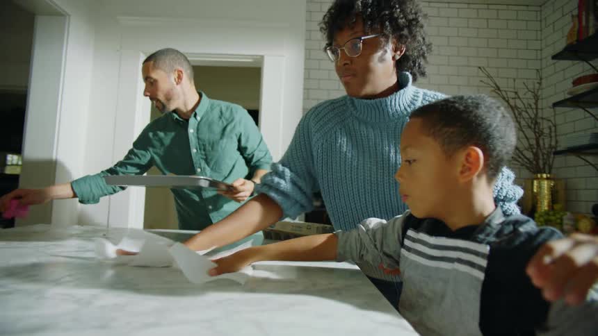 Family of four cleaning the kitchen counter top after cooking cookies