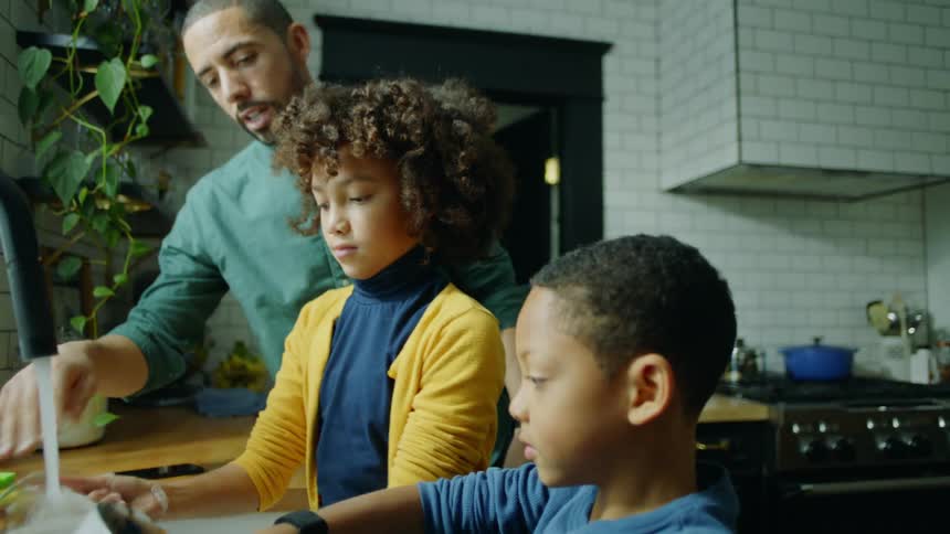 Family washing the dishes in the kitchen sink at home