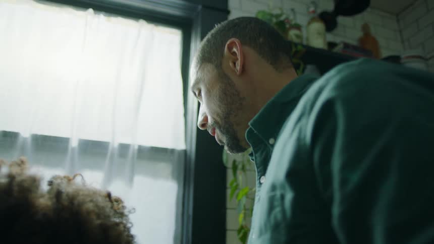 Father stands near kids as they wash dishes in foamy water