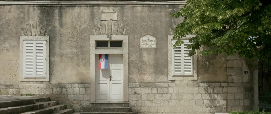 A stone building has a flag on the front door