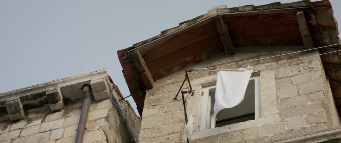 A towel hangs from a line outside an old building during the day