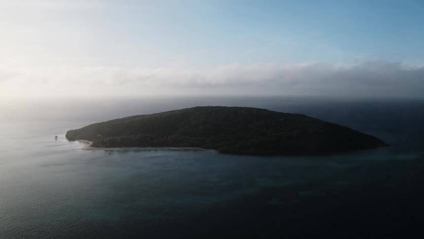 A verdant island on the ocean during the day