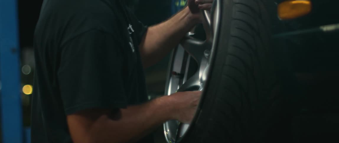 A mechanic carries a tire to place on a vehicle