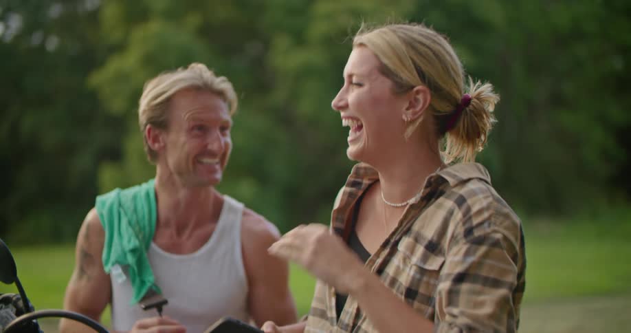 A man and woman laugh and talk outside