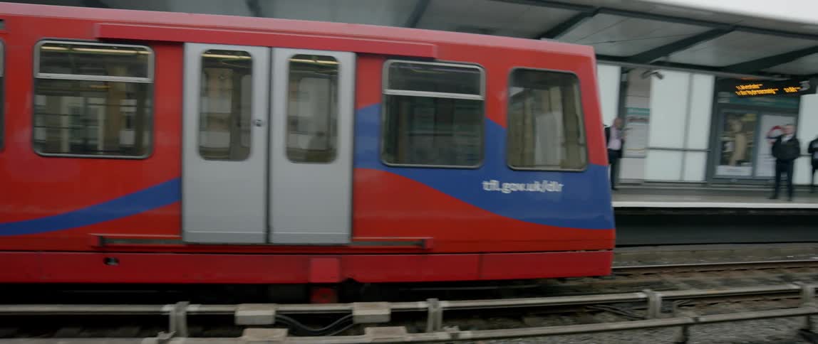 A commuter train pulls into a station on an overcast day