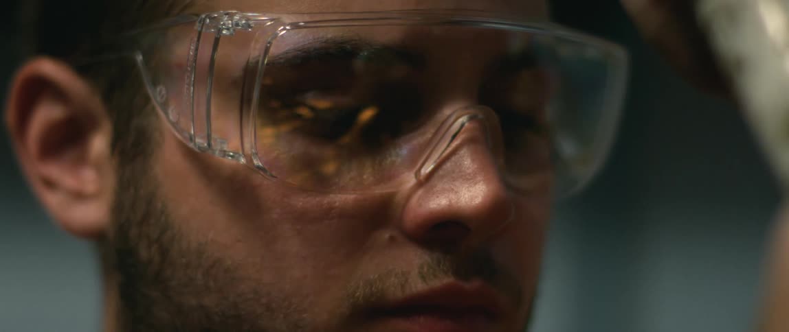 A man concentrates as he welds while the sparks reflect on his goggles