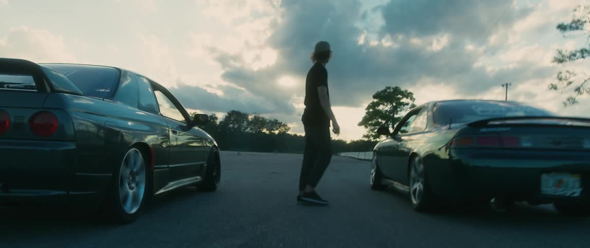 A man waves two cars off on a race
