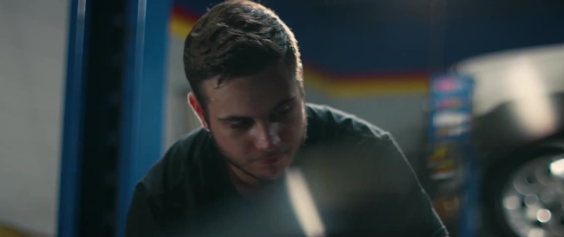 Young man shakes his head as he examines a vehicle in an auto shop