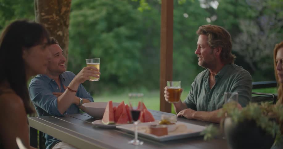 Group of friends drinking and talking on a table in the porch at evening