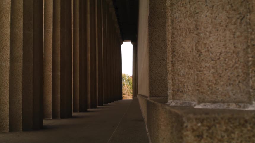 Thick scalloped columns line the outdoor corridor of a historical building