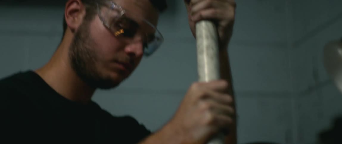 An employee grinding a metal rod in a shop with sparks